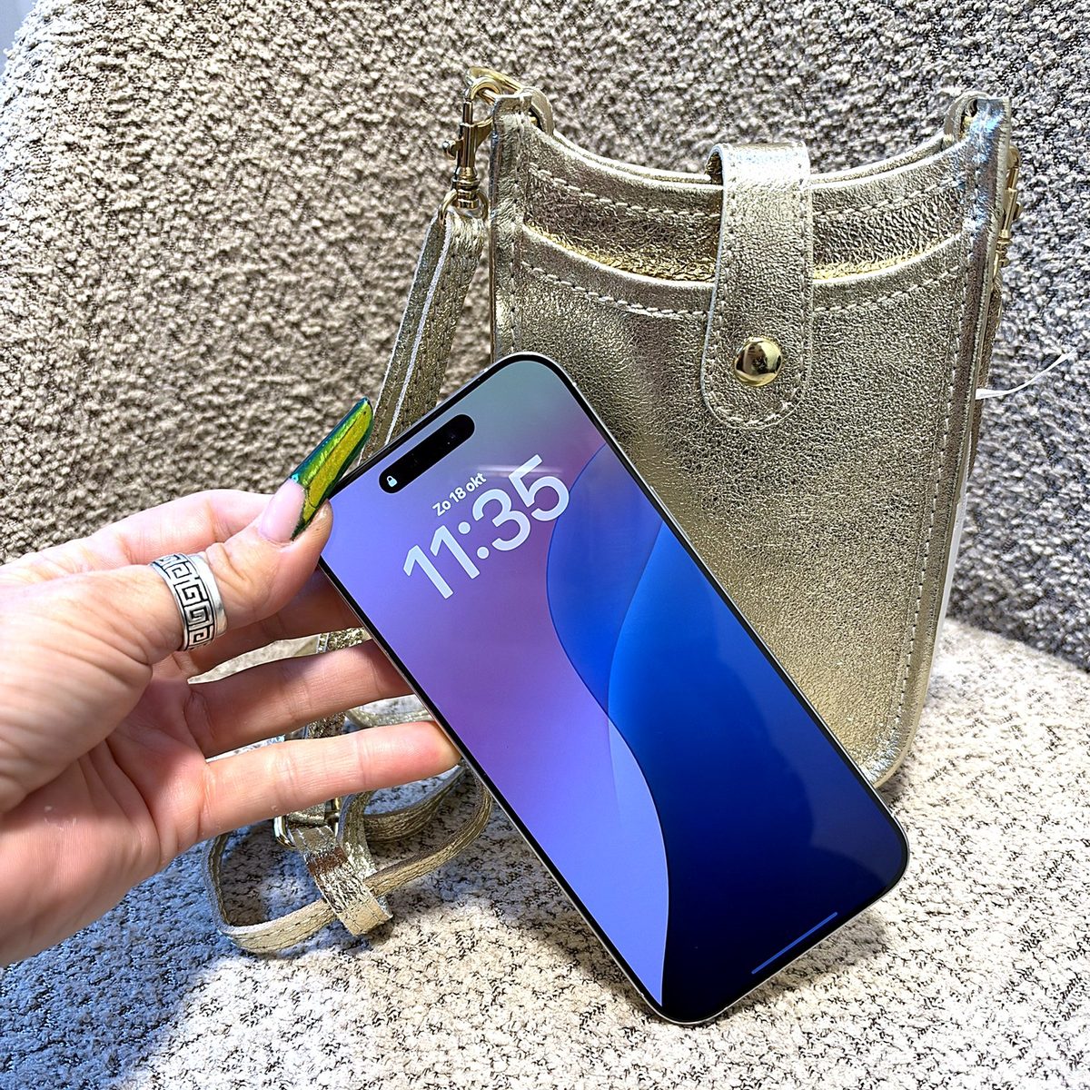 Gouden leren telefoontasje met smartphone in de hand