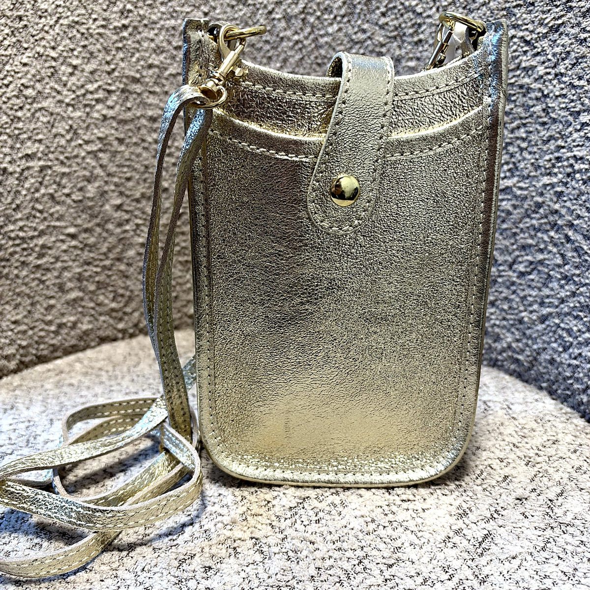Gouden leren telefoontasje met drukknoop en schouderband